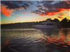 Red and gray clouds overlooking a boat on the lake during sunset
