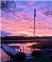 View of the lake, dock, and flag overlooking a multicolored sky in blue, purple, pink, and orange