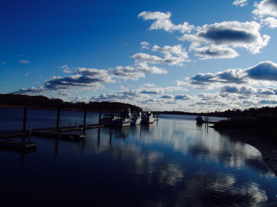 Boats docked at a lake under the blue sky and clouds 